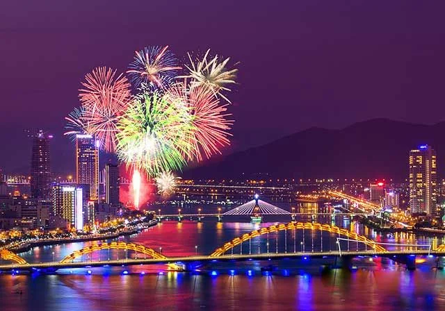 Khai phá pháo hoa đêm trên dòng sông của thành phố với cầu và tòa nhà sáng đèn.